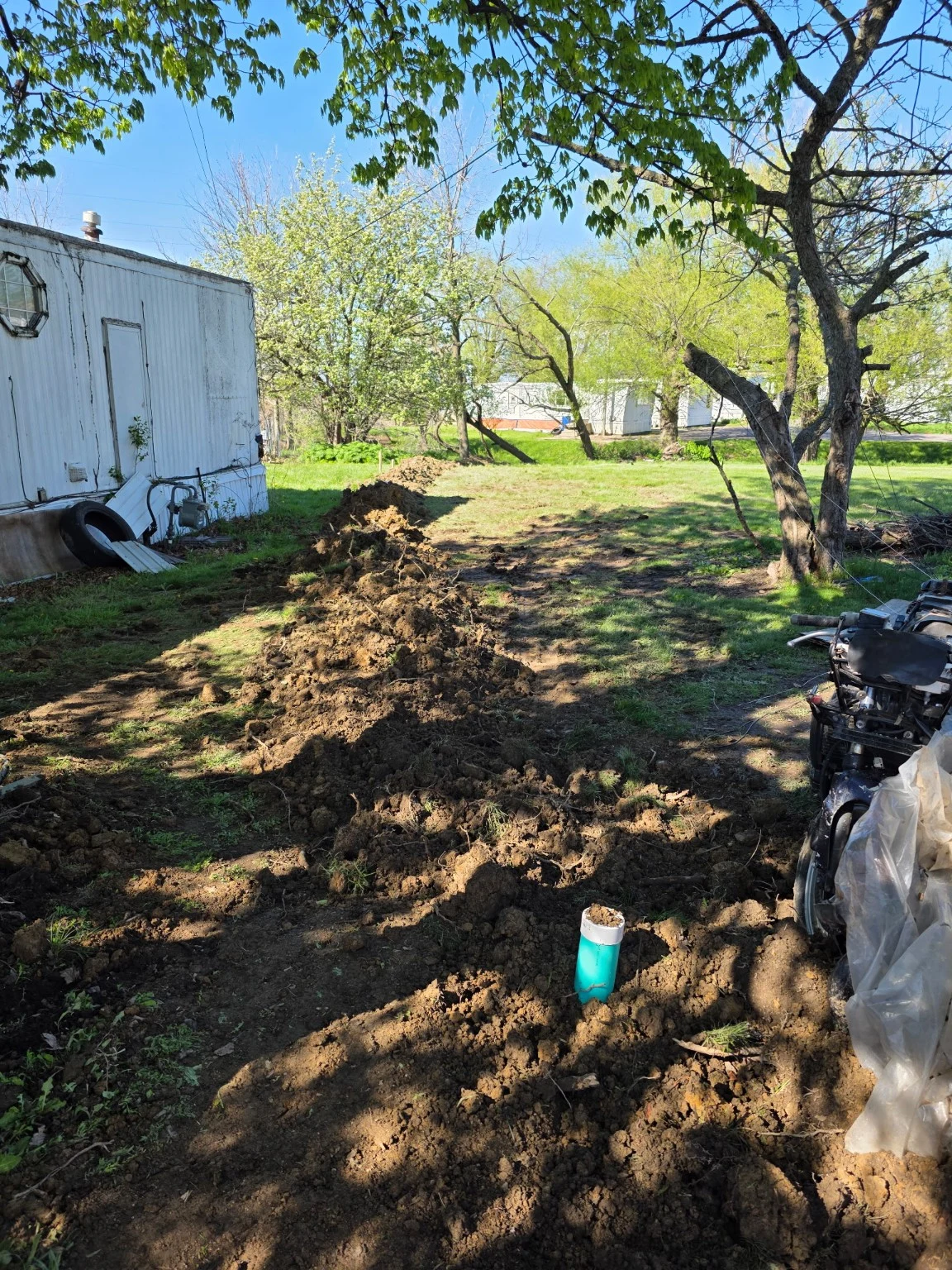 Soil backfilled along a pipe trench beside a building