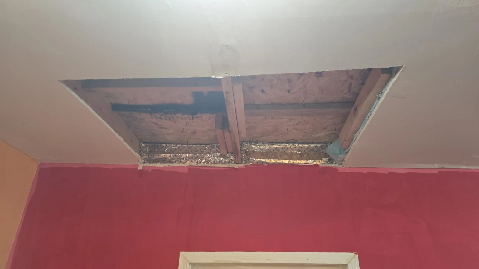 Interior ceiling opening exposing wood framing