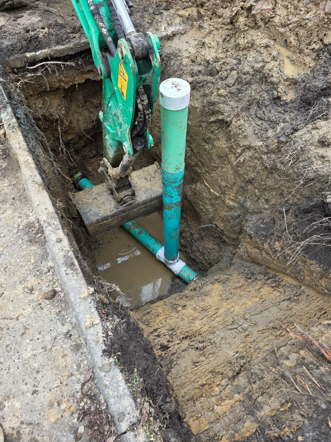 Exposed underground pipe and excavator bucket in a trench