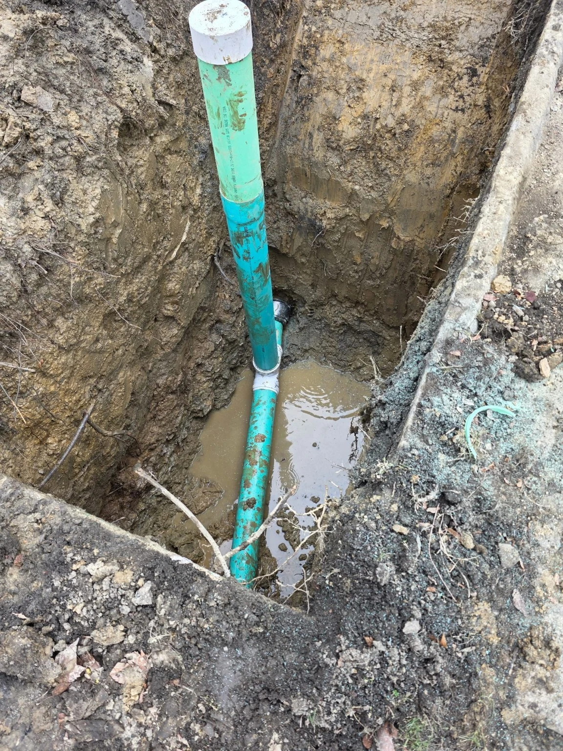 Vertical pipe exposed in an excavated trench